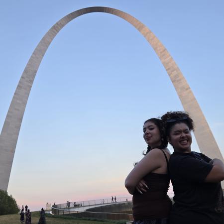 aj and alli posing back to back in front of the St. Louis arch