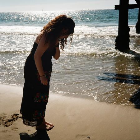 Alli looking at a baby crab on the sand